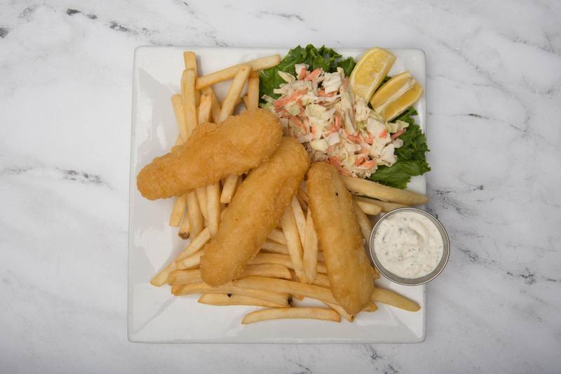 Three pieces of battered cod on fries, with coleslaw, lemon wedges and tartar sauce