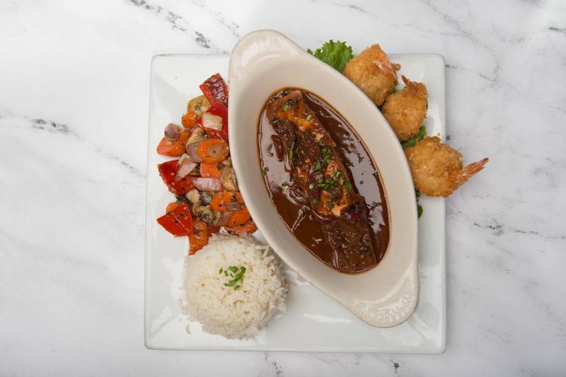 Salmon in a dark red wine sauce with three coconut prawns, sautéed vegetables and rice